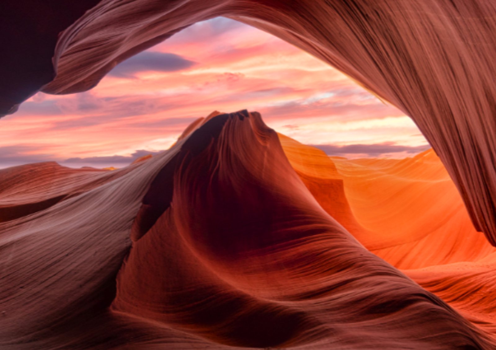 A sandstone arch opening onto a sunset sky